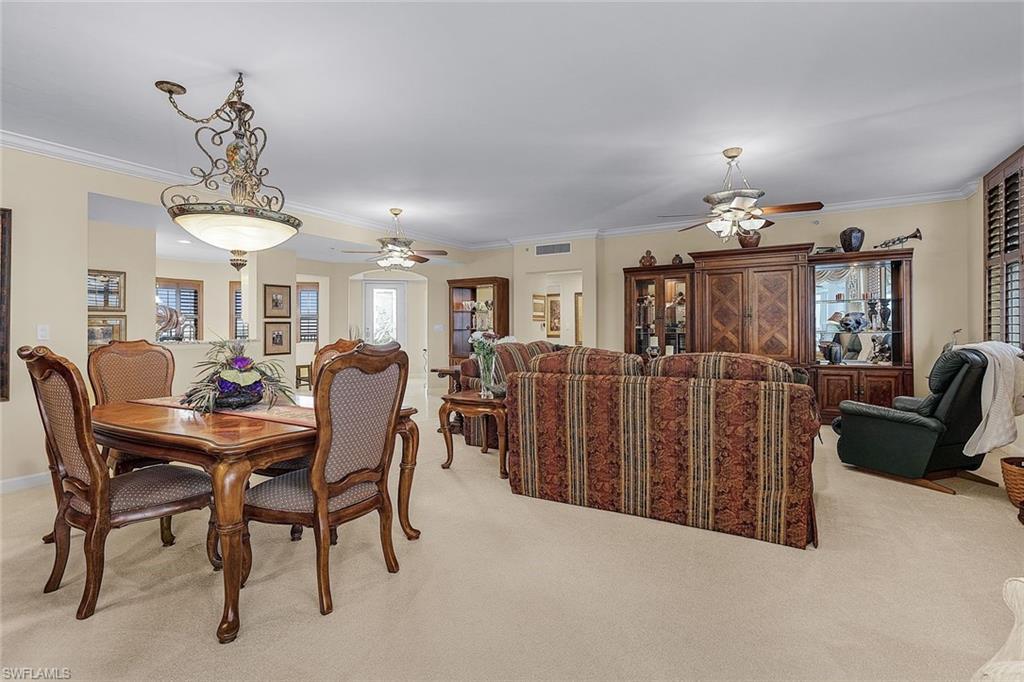 Dining area with ornamental molding, light colored carpet, and ceiling fan
