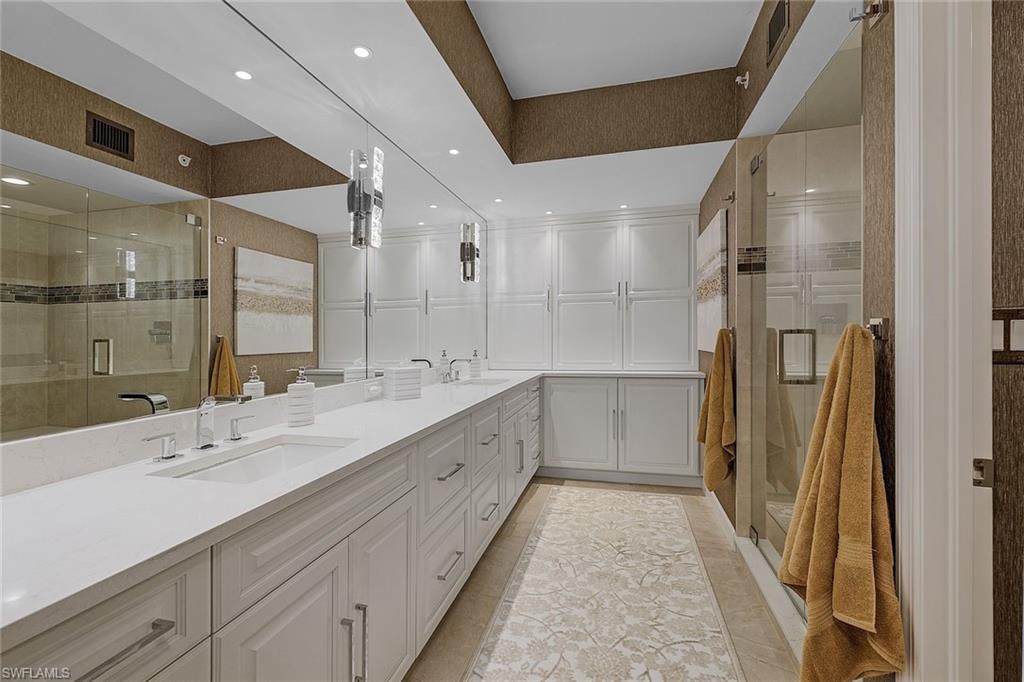 Full bath featuring a stall shower, double vanity, recessed lighting, and light tile patterned floors