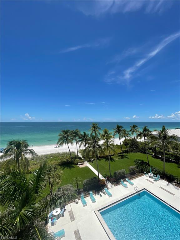 Community pool with view of water and beach, a yard, and a patio area