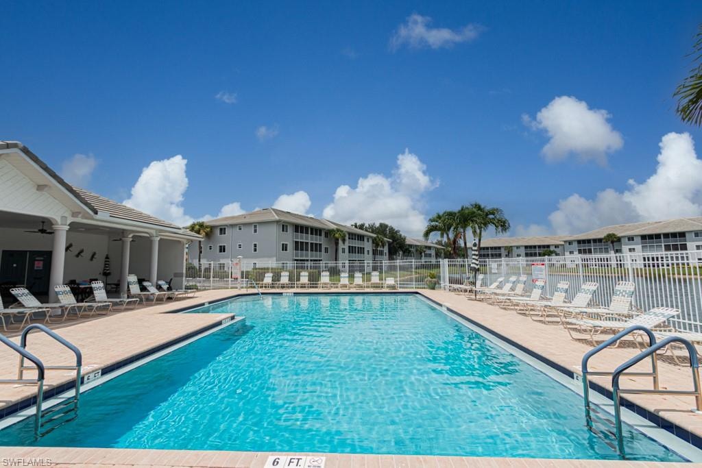 Community pool with a patio area, a ceiling fan, and a residential view