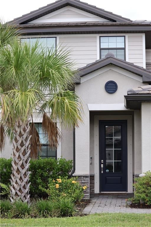 Entrance to property featuring stone siding and stucco siding
