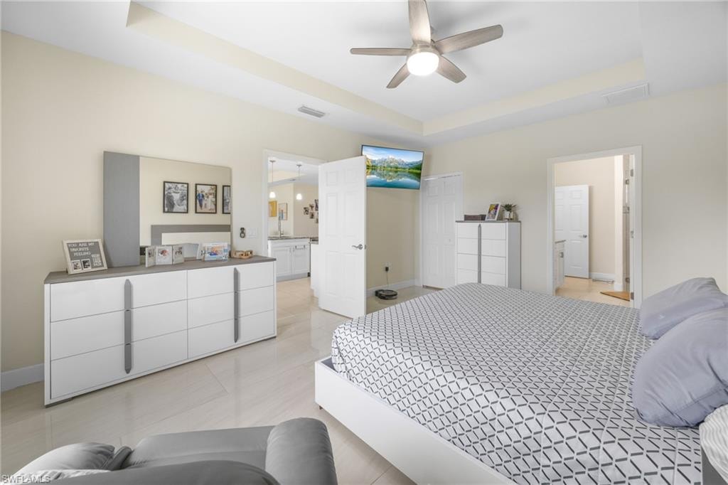 Bedroom featuring a raised ceiling, a ceiling fan, and light tile patterned flooring