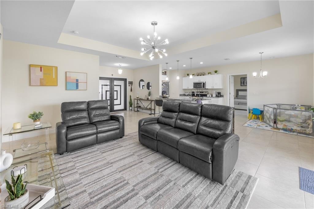 Living area with a chandelier, a raised ceiling, and light tile patterned flooring