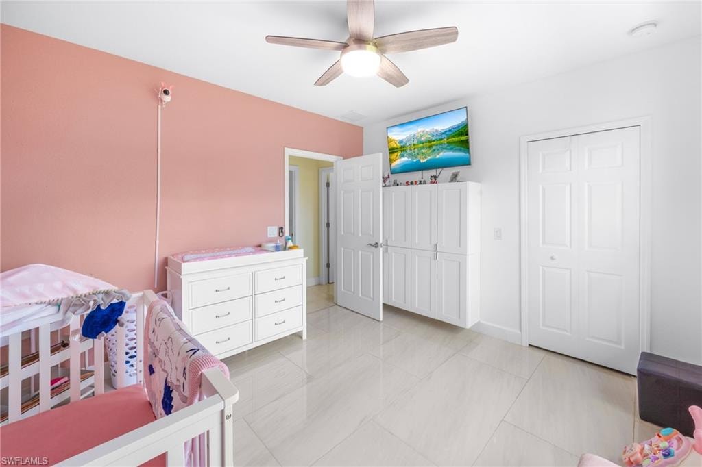 Bedroom with light tile patterned flooring, a ceiling fan, and a closet