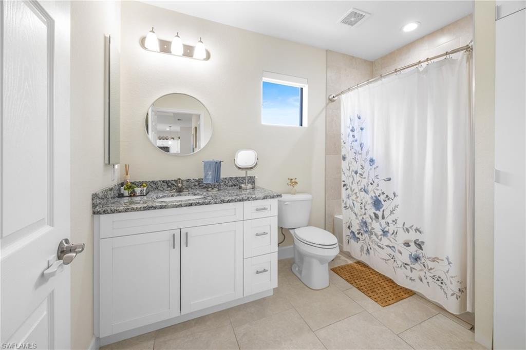 Bathroom featuring shower / bathtub combination with curtain, vanity, and light tile patterned floors