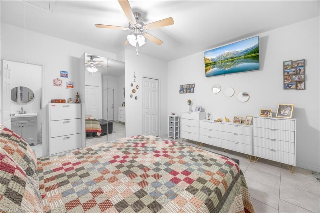 Bedroom with attic access, ceiling fan, light tile patterned floors, a closet, and connected bathroom