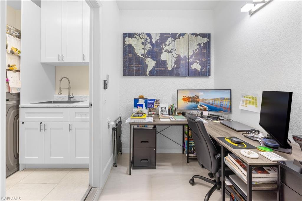 Home office with a textured wall, washer / clothes dryer, and light tile patterned flooring