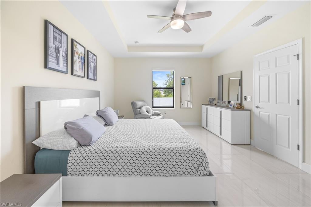 Bedroom featuring a raised ceiling, ceiling fan, and light tile patterned floors
