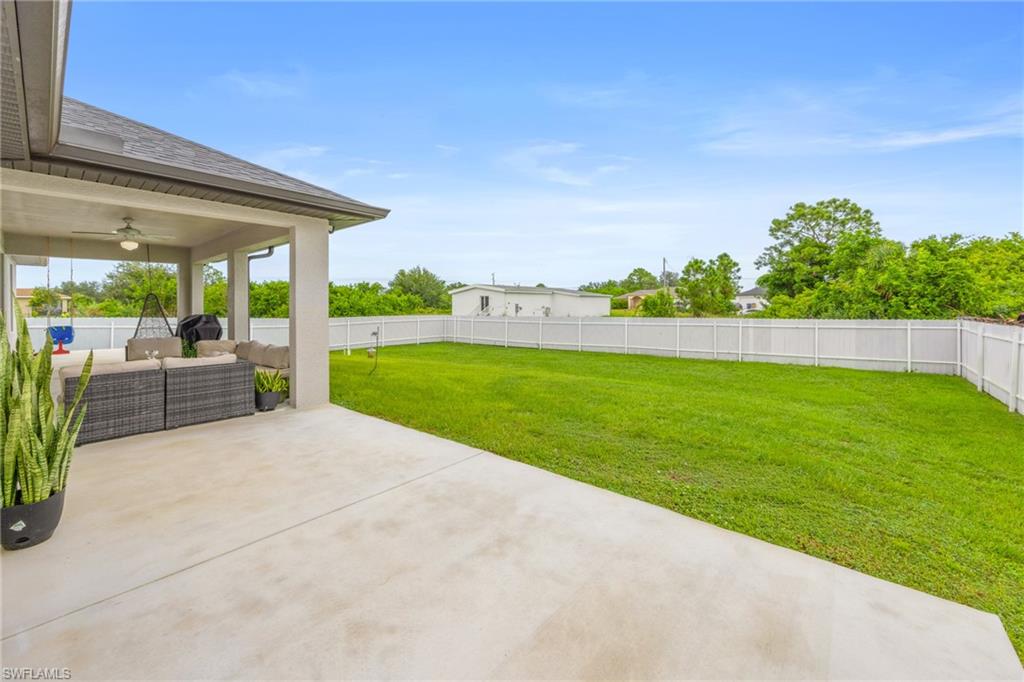 Fenced backyard featuring a patio area, an outdoor living space, and a ceiling fan