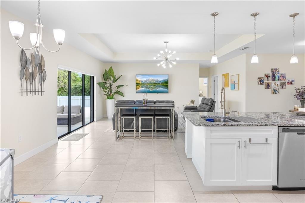Kitchen featuring a chandelier, pendant lighting, a raised ceiling, and open floor plan