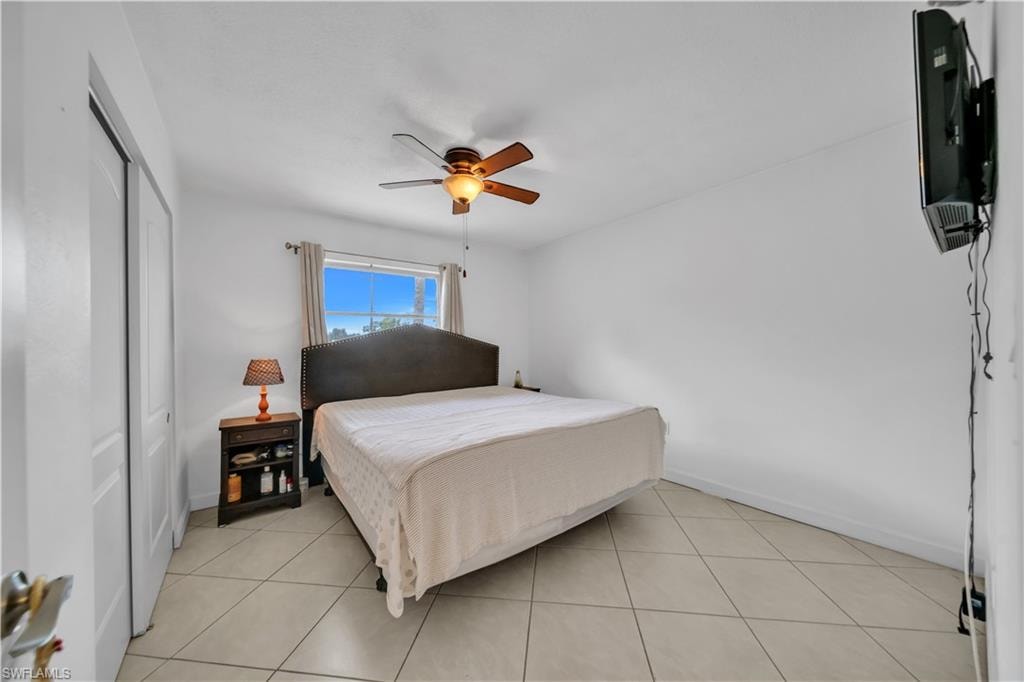Bedroom with light tile patterned floors, a ceiling fan, and a closet