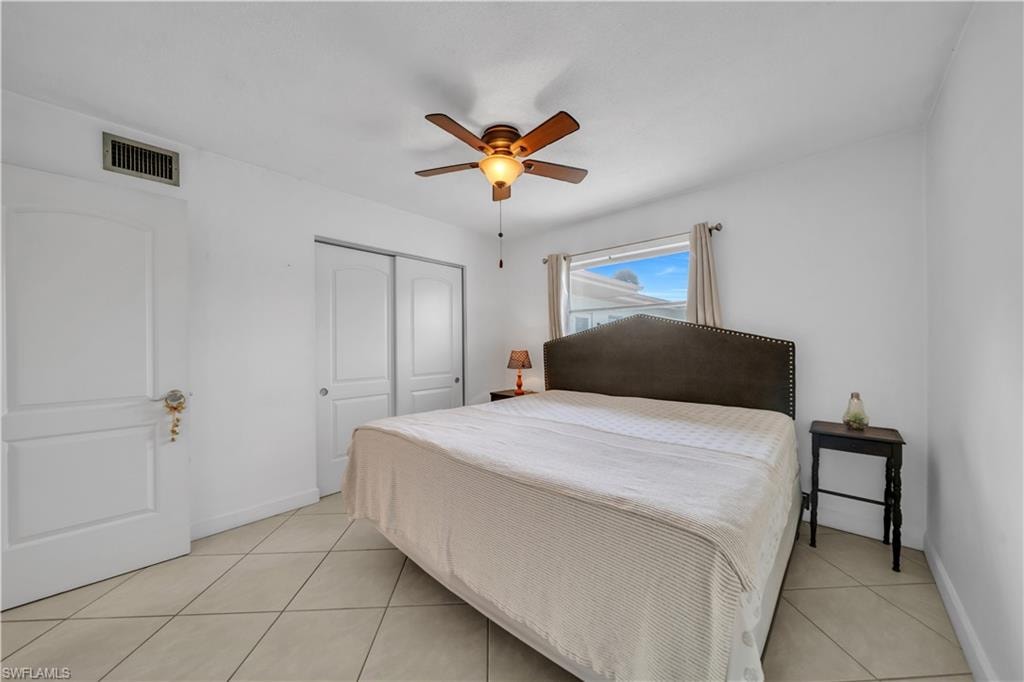 Bedroom with light tile patterned floors, a closet, and a ceiling fan