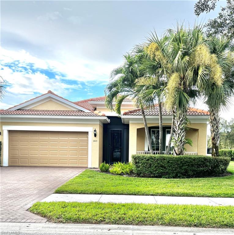 View of front facade featuring decorative driveway, stucco siding, a front yard, and a garage