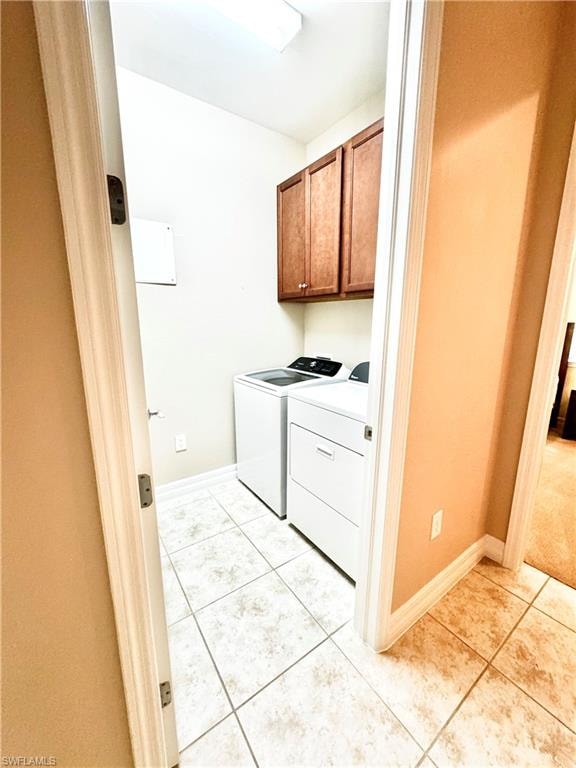Washroom with cabinet space, light tile patterned floors, and washer and dryer