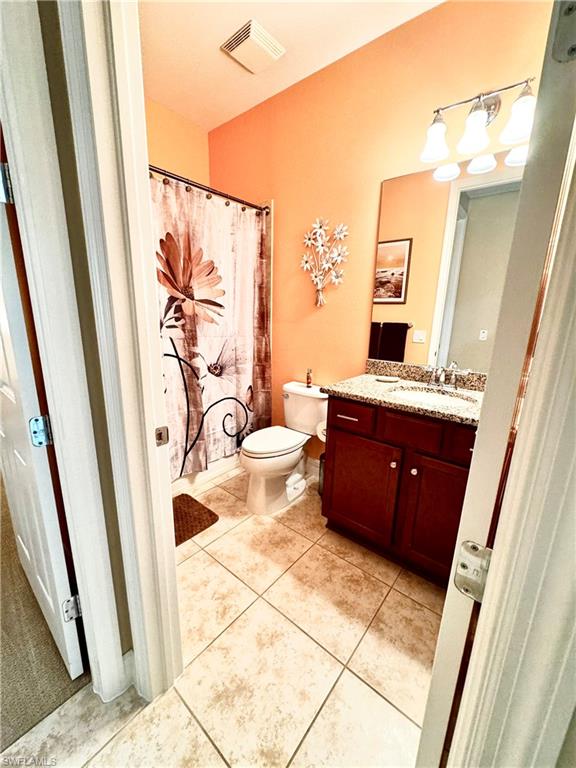 Bathroom featuring vanity, light tile patterned flooring, and a shower with shower curtain