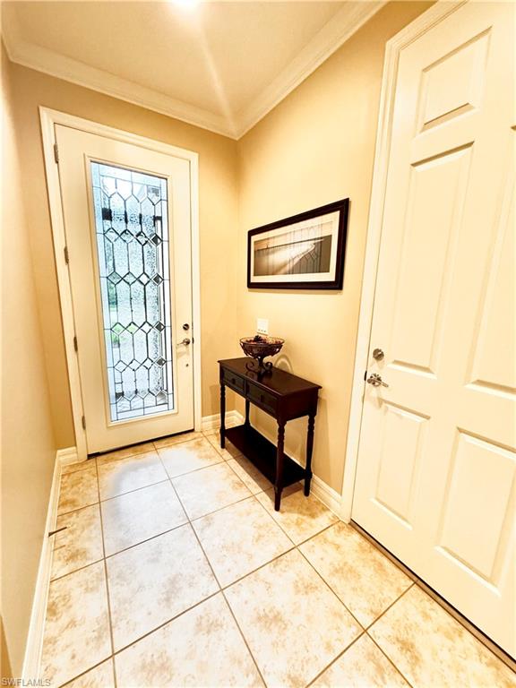 Foyer entrance with crown molding and light tile patterned floors