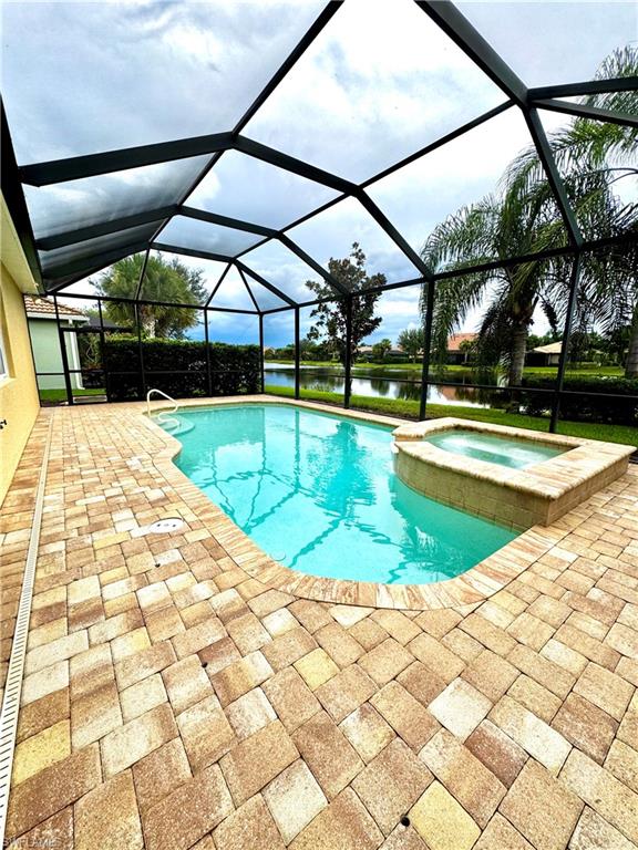 View of pool with a sunroom, a water view, a lanai, a patio, and a pool with connected hot tub