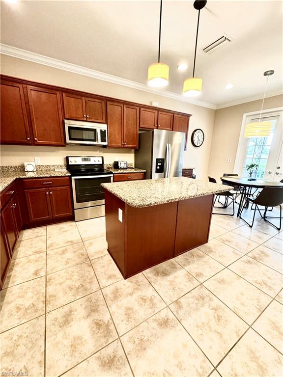 Kitchen featuring ornamental molding, decorative light fixtures, appliances with stainless steel finishes, light stone countertops, and light tile patterned floors