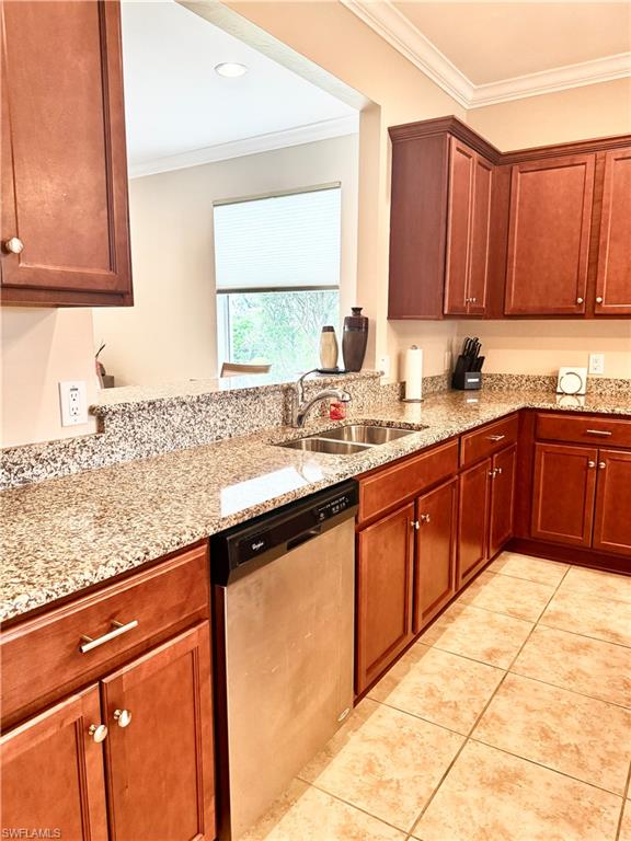 Kitchen featuring crown molding, stainless steel dishwasher, light stone counters, light tile patterned floors, and brown cabinetry