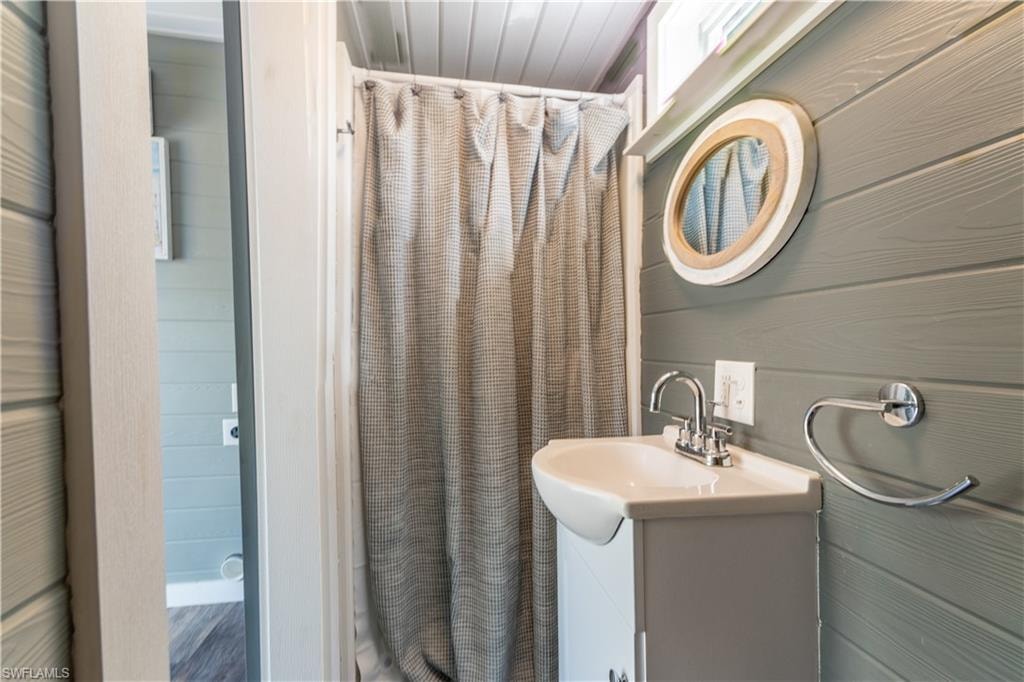 Full bathroom featuring vanity, curtained shower, and wooden walls