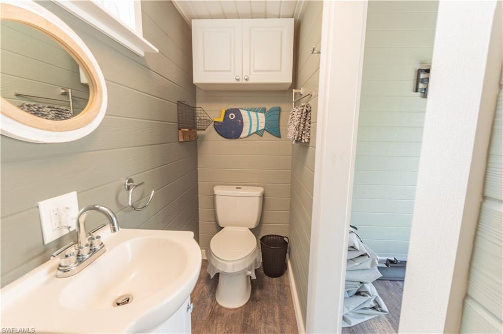 Half bathroom featuring dark wood-style flooring and wood walls