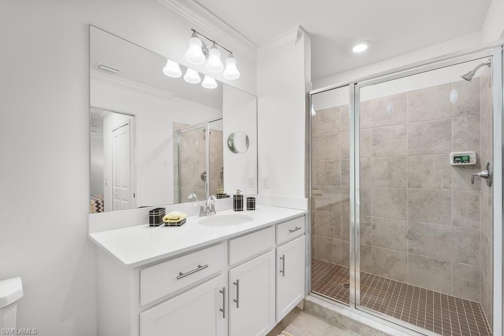 Bathroom featuring a stall shower, vanity, and ornamental molding