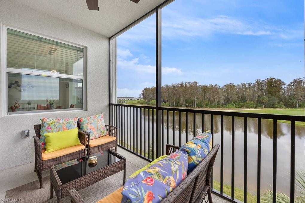 Balcony with a water view, view of wooded area, and ceiling fan