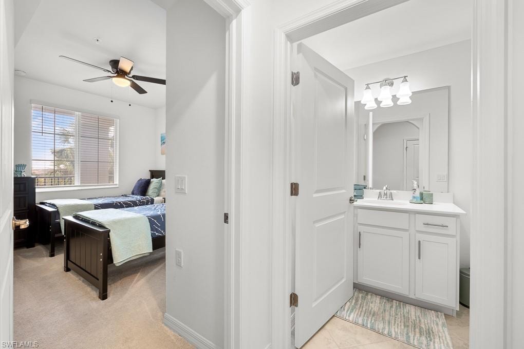 Bathroom featuring vanity, connected bathroom, ceiling fan, and light tile patterned floors