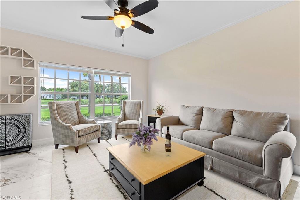 Living room featuring ornamental molding, a ceiling fan, and marble look tiles