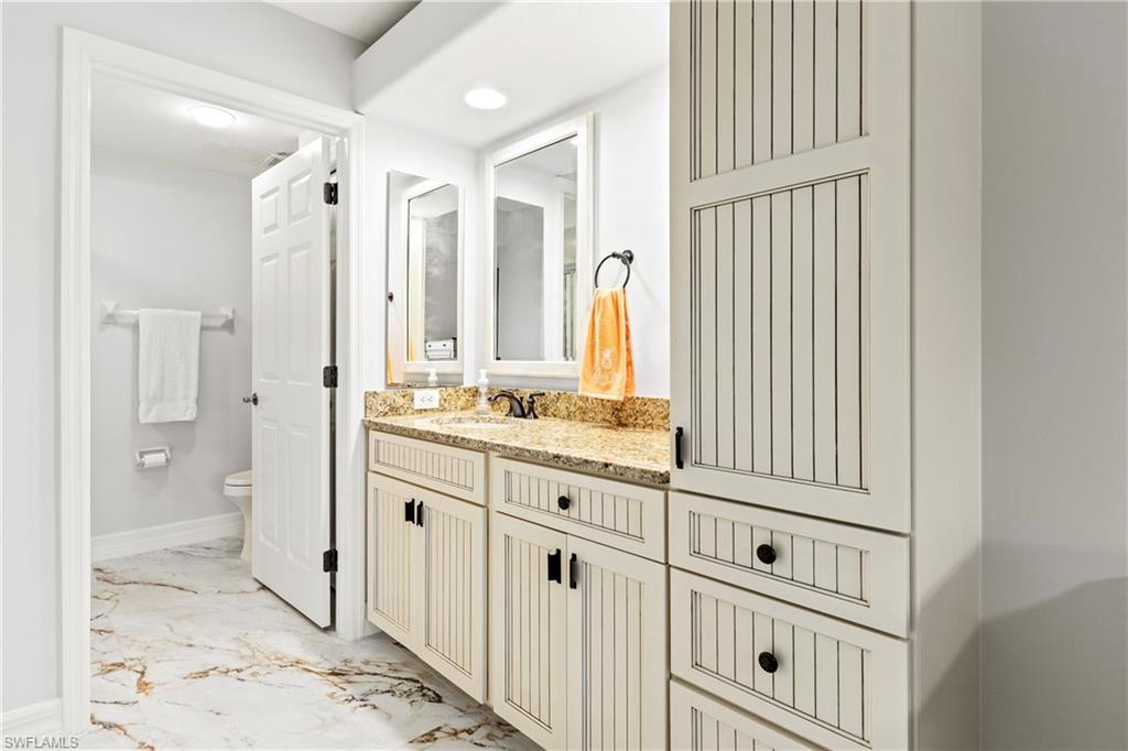 Full bathroom featuring light marble finish floors, vanity, and recessed lighting
