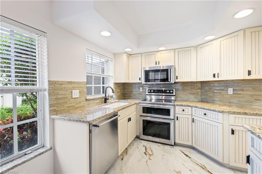 Kitchen with light marble finish floors, cream cabinetry, stainless steel appliances, light stone counters, and recessed lighting
