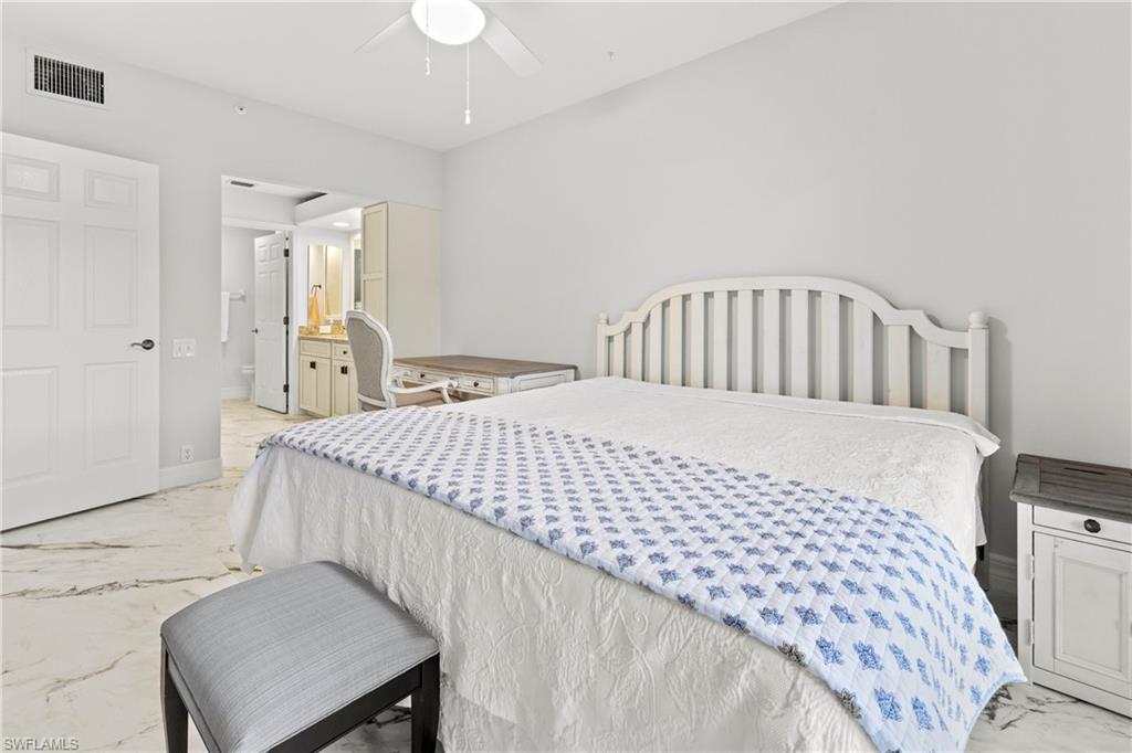 Bedroom featuring light marble finish floors, ensuite bathroom, and a ceiling fan