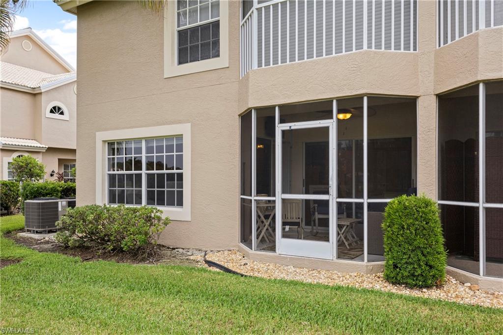 Rear view of house featuring stucco siding, a sunroom, and a yard