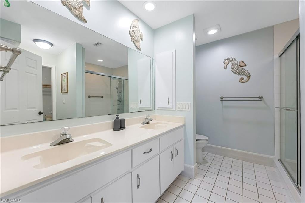 Full bath featuring double vanity, a stall shower, light tile patterned flooring, a walk in closet, and recessed lighting