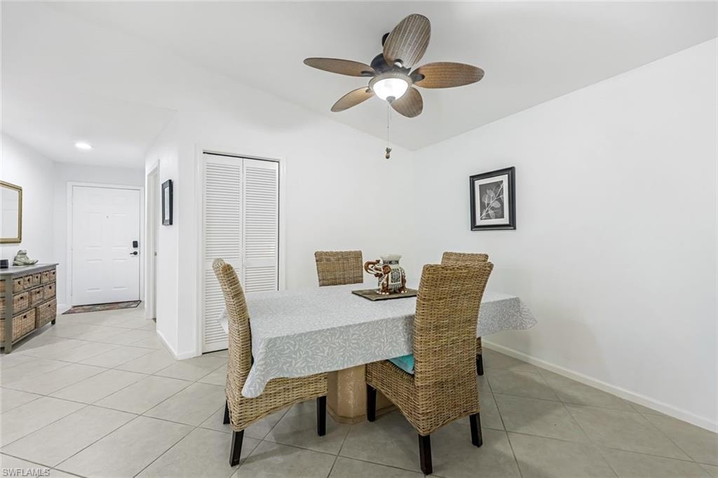 Dining area featuring light tile patterned floors, vaulted ceiling, and a ceiling fan