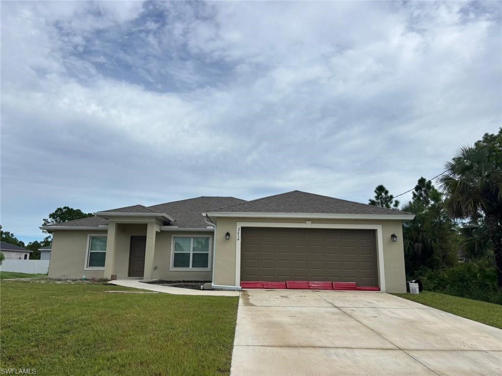 View of front facade with stucco siding, a shingled roof, and concrete driveway