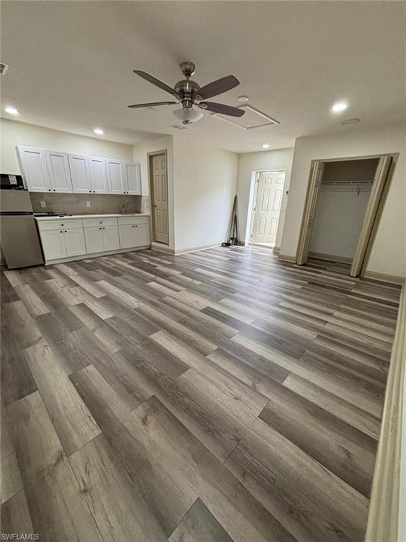 Unfurnished living room with recessed lighting, light wood-style flooring, ceiling fan, and attic access