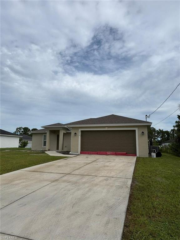 Ranch-style house featuring stucco siding, a front yard, driveway, and a shingled roof