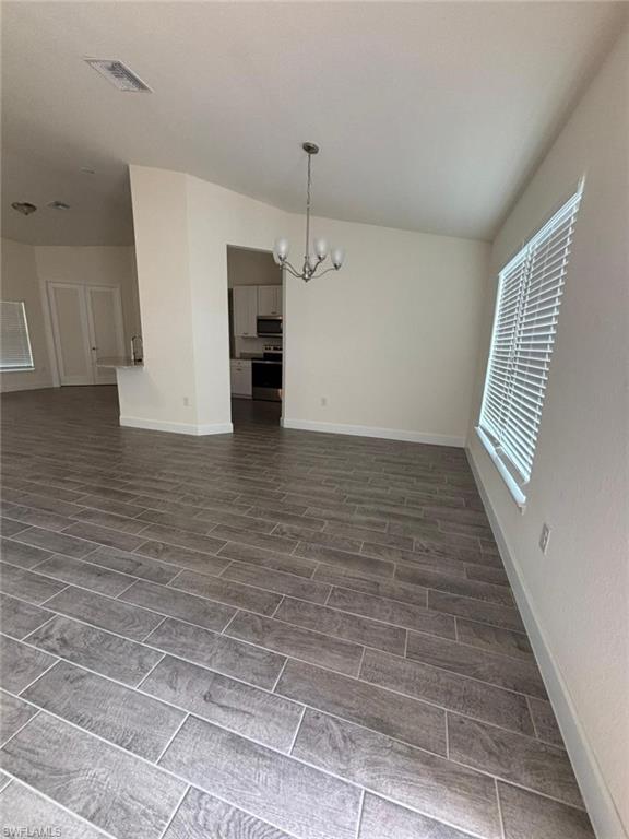 Unfurnished dining area with a chandelier and wood tiled floors