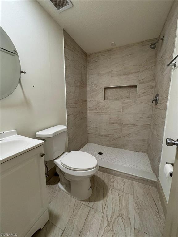 Full bath featuring vanity, a shower stall, and a textured ceiling