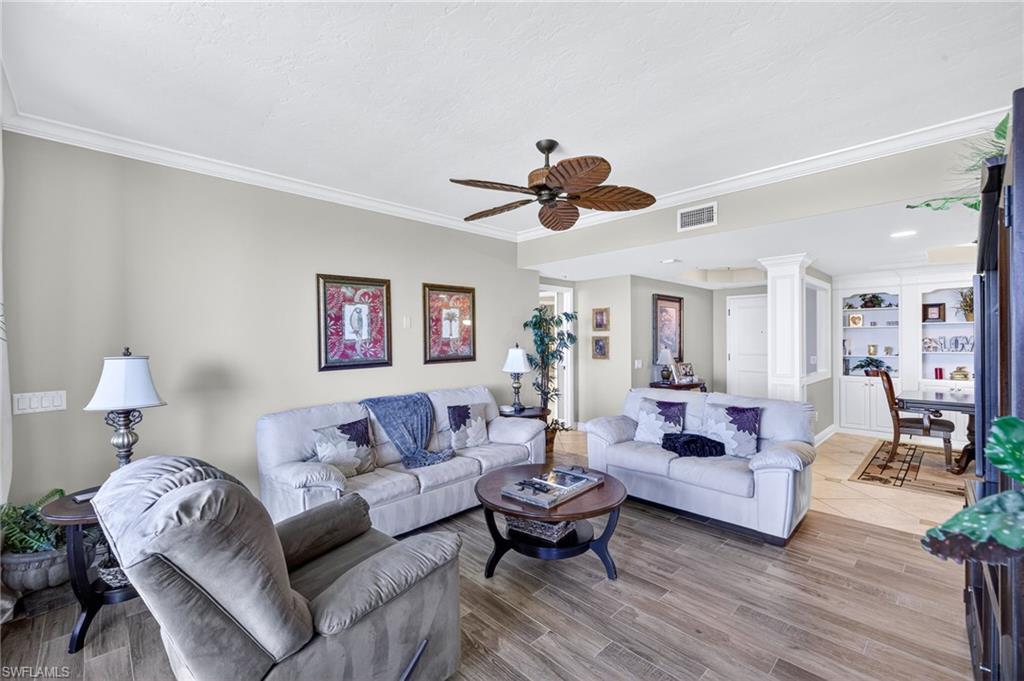 Living room with a ceiling fan, crown molding, and light wood-style flooring