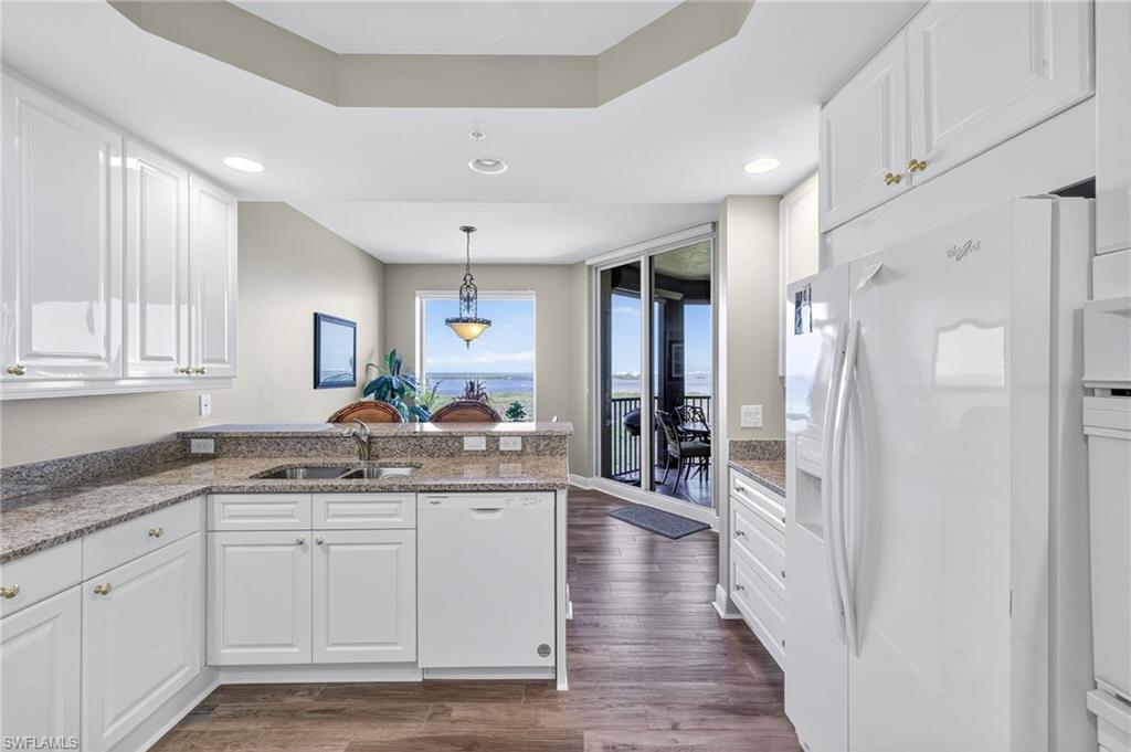 Kitchen featuring white cabinetry, a peninsula, white appliances, light stone countertops, and recessed lighting