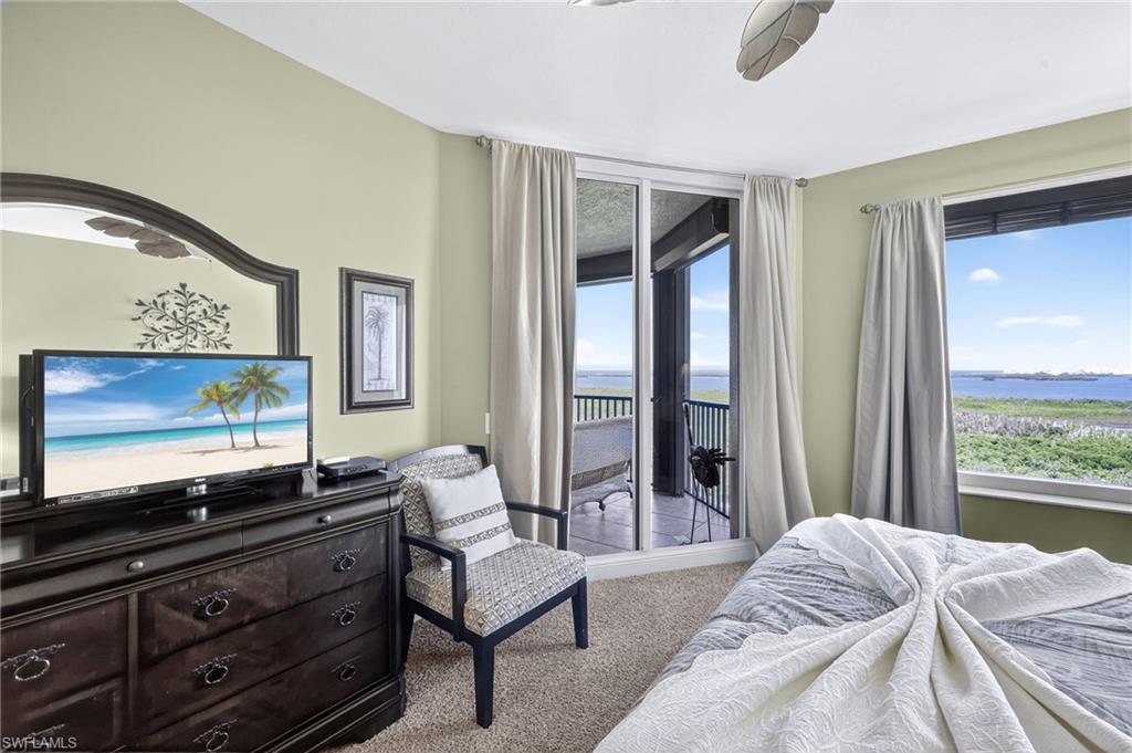 Bedroom with light carpet, multiple windows, access to outside, and a water view