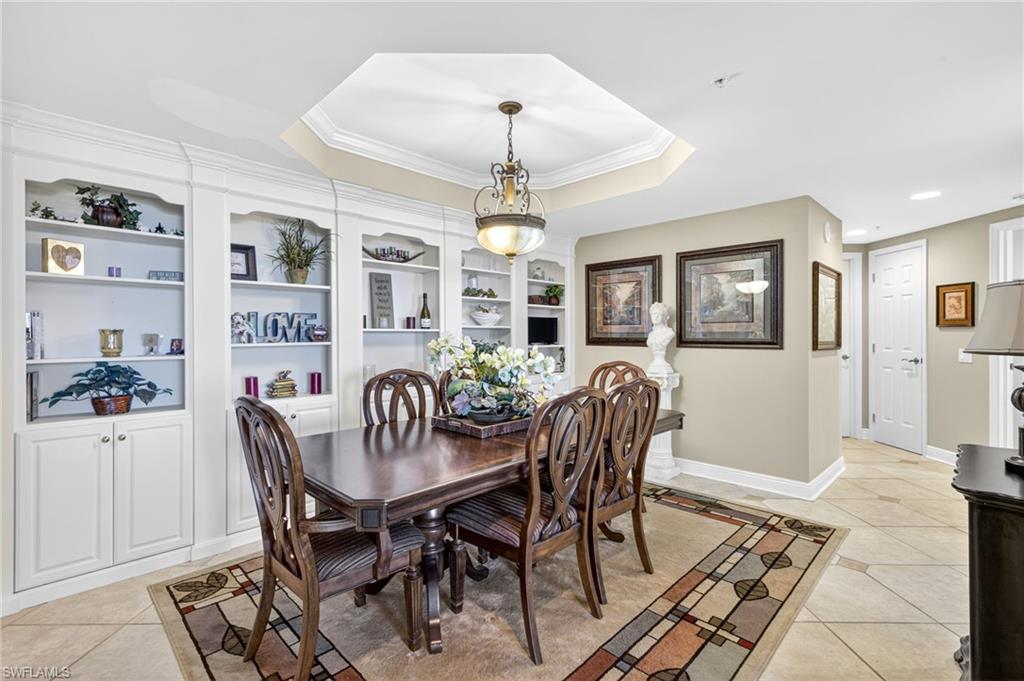 Dining room featuring light tile patterned floors, a tray ceiling, and crown molding