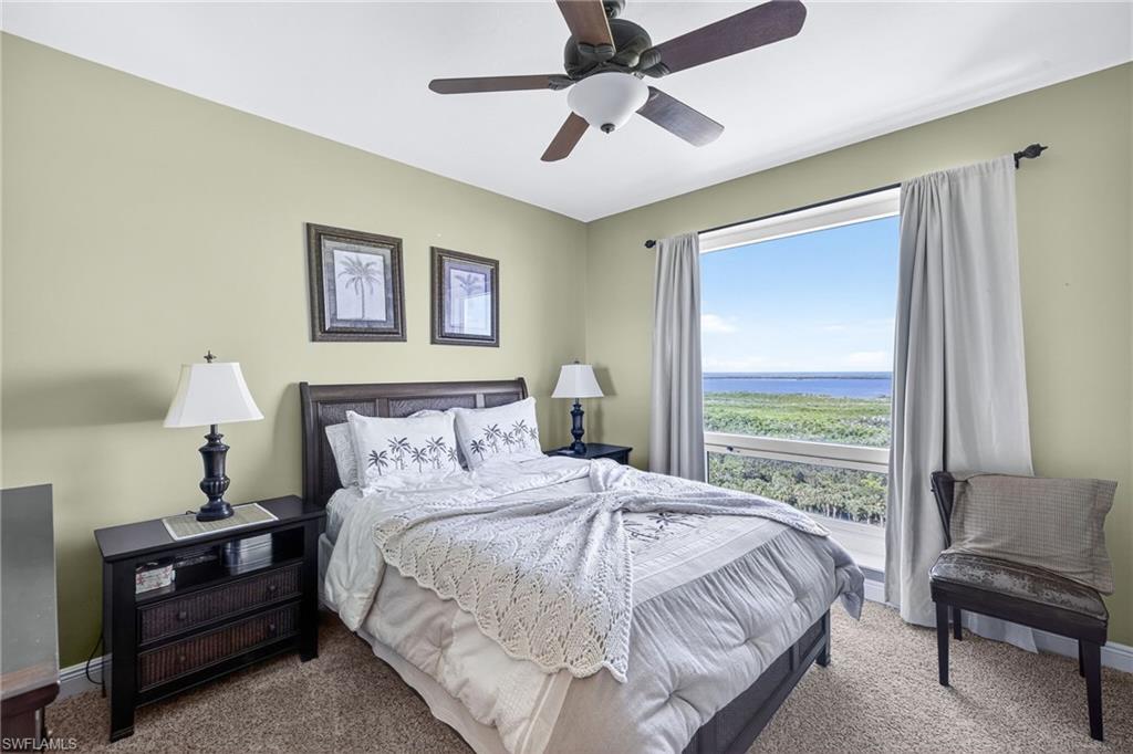 Carpeted bedroom featuring ceiling fan and a water view