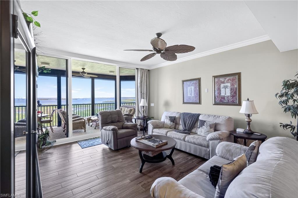 Living area featuring expansive windows, a water view, crown molding, wood finished floors, and a ceiling fan