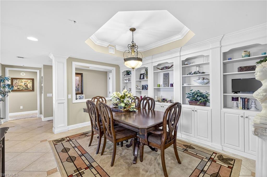 Dining space with ornate columns, a raised ceiling, light tile patterned floors, ornamental molding, and recessed lighting