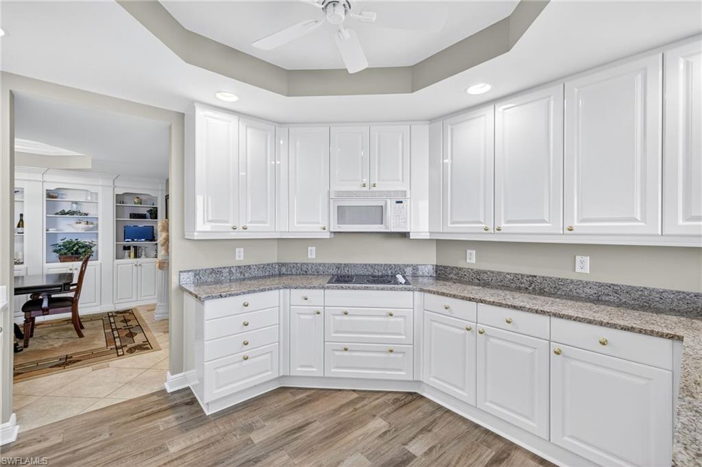 Kitchen featuring a tray ceiling, light stone countertops, recessed lighting, and white cabinets