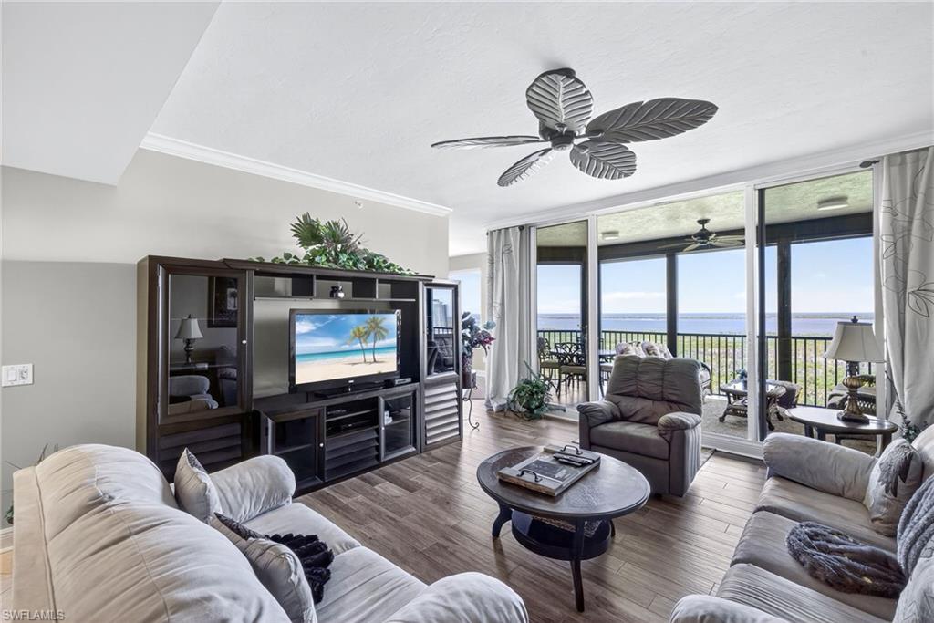 Living area with floor to ceiling windows, crown molding, wood finished floors, and a ceiling fan