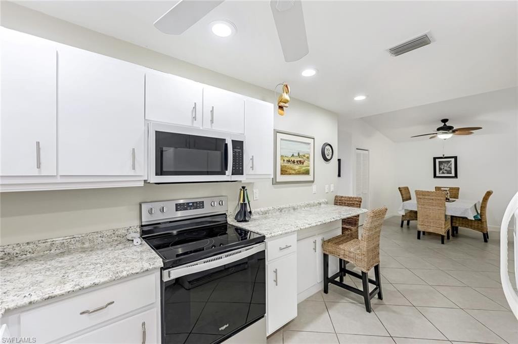 Kitchen with stainless steel electric range oven, ceiling fan, white microwave, white cabinetry, and recessed lighting